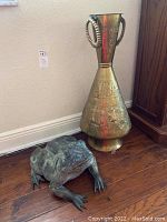 Both the brass vase and the frog sculpture positioned side by side on the floor showing full item scale and condition.