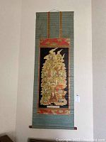 Asian antique or vintage scroll hanging on wall, showing full length and design with multiple figures and border.