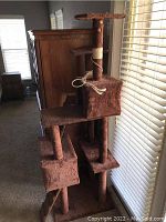 Full side view of six-level cat tree climbing frame showing multiple platforms, steps, two cubby holes, carpet covering and cat claw damage