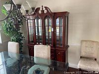 Full front view of the vintage oriental style china cabinet in a dining room setting, showing glass doors and drawers below.