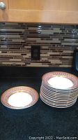 Set of 13 soup or salad bowls stacked with one bowl out front on black countertop, kitchen backsplash in background.