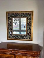 Full view of square mirror framed with wood and fabric showing some scratches in frame.