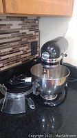 Mixer with bowl, whisk, and pouring shield on counter