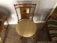 Full view of vintage faux bamboo design metal parlor chair with upholstered round beige seat, showing palm tree panel on backrest.