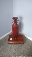 Full view of red floor vase on wooden stand, showing overall lot contents.