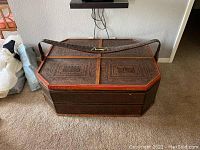 Front view of octagonal carved Oriental dowry chest with lid closed and textured strap handle.