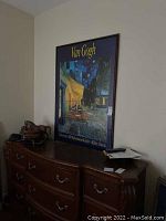 Framed Van Gogh poster hanging on wall above furniture, showing full height and partial width of frame.