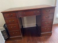 Front view of wooden vintage sewing machine desk with drawers and brass tone pulls.