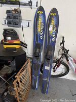 Two blue Jobe Allegre water skis standing upright showing overall condition including bindings and scratches.