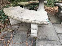 Front angle of curved concrete bench showing decorative oval border and scroll pedestal supports