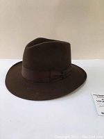 Front-right angled view of brown felt fedora hat, showing shape and grosgrain band.
