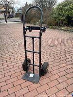 Dolly in upright position with handle extended and toe plate folded down, showing pneumatic wheels and metal frame