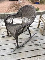 Side view of brown synthetic wicker patio rocking chair showing woven seat, armrests, and metal rocker base.