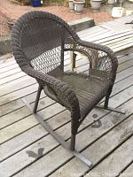 Brown woven outdoor patio rocking chair on a deck, showing front view and seat design.