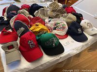 Overview of multiple baseball caps, visors, pinwheel caps and a sun protection cap on a table.