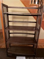 Front view of the folding wood bookcase showing four shelves and vertical slat sides.
