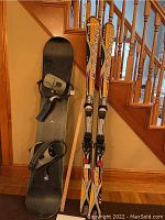 Sin snowboard standing next to Blizzard skis with ruler for length reference