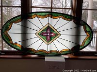 Full front view of oval stained glass panel showing overall design and color scheme.