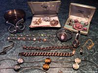 Overview of various bracelets, rings, watch, cuff and two jewelry boxes containing brooches and earrings