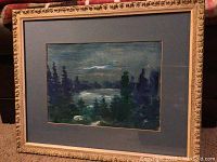 Framed dark moody landscape artwork with blue mat and ornate gold frame.