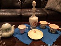 Photo of all items together, including decanter, various teacups, and dish