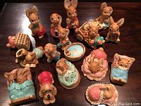 Full set of about 16 Pendelfin rabbit figurines in various poses and outfits displayed on a dark wooden surface.