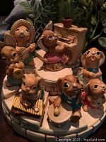 Close-up of 8 Pendelfin animal musician figurines arranged on tiered stone display with foliage in background.