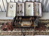 Overview of flatware sets in packaging and serving tray with utensils arranged on decorative table runner