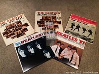 Overview of the set showing five Beatles LP vinyl albums and the Anthology cassette set stacked vertically in the center.