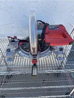 Front view of the 10-inch SKIL compound miter saw showing blade guard, handle, and setup on metal rack.