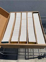 Top-down view of a box filled with neatly stacked trading cards, divided into 5 sections within the box.