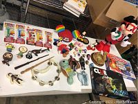 Wide view of all toys and games on table showing PEZ dispensers, figurines, plush, wands, board games, and tambourines.
