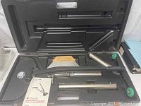 Carpet stretcher inside molded metal case with extension tubes and long handle