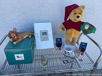 Full lot displayed on metal cart showing statuette, plush, mugs, coin box, and pins