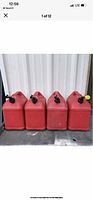 Four red Blitz 5 gallon gas cans lined up side by side, showing all have black caps on top and rectangular shape.