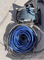 View of three pneumatic air hoses, one coiled on broken reel, others loose on ground.