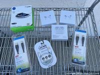 Photo showing all items in the lot including Belkin wireless charger box, two Apple AirPods Pro sealed boxes, two USB 2.0 cables in packaging, and one Lightning to USB cable with adapters.