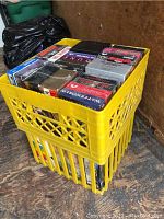 Photo showing two stacked yellow crates filled with VHS tapes. Many tapes are visible with intact covers, in good condition, some still in original shrink wrap.