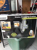 View of the front of the box showing product name, a diagram of the massage mechanism inside the cushion, illustration of the remote control, and features of the product.