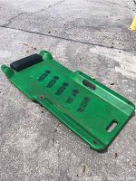 Green Matco Tools mechanics creeper on concrete with black foam headrest, detailed logo and model impressions visible