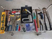 Metal shelf cart displaying the tools including levels, pliers, staple gun, wire strippers, razor cutter, screwdrivers, tape measure and Dremel accessories