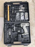 Full view of the tool set showing the hammer, pliers, screwdrivers, drill bits, cordless drill with charger and battery packed in the black molded plastic case.