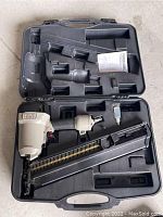 Opened plastic carrying case contains the Porter Cable pneumatic framing nailer, manual, and magazine.