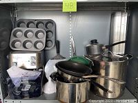 Full view of all items stacked in a metal rack including baking trays, pots, pans, spatula, and the coffee machine.