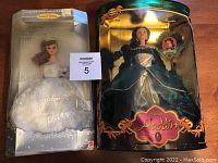 Two boxed Barbie dolls side by side; Wedding Barbie in white gown and Disney Aladdin Princess Jasmine in green dress