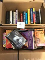 Box with assorted books, showing top covers including 'Fifty Shades Darker', 'Hamlet', and a purple book titled 'Law and Orders'.