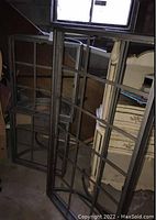 Photo showing two matching end tables with metal grid frames and removable glass tops, stacked in a basement setting.