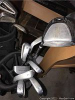 Close-up of golf clubs including irons numbered 5, 6, 7, 8, 9 and a driver or wood.