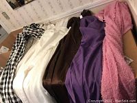 Seven curtain panels including black and white checkered, brown, purple, and white panels laid out on a surface