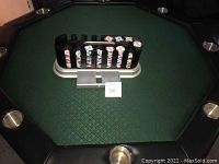 Poker chips arranged in a black plastic chip holder on the green felt poker table surface, showing the poker chip colors and design.